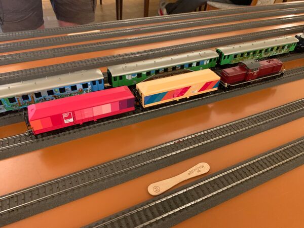 Schwere Rangierlokomotive Baureihe V 90 mit PANTONE Sonderwagen. Vorne liegt ein Stiel von einem Eis, der zum Entkuppeln verwendet wird.